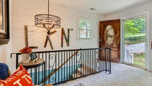 A foyer with a staircase, a chandelier, and a wooden door with a glass panel. - Locke Haven (Sherrills Ford)