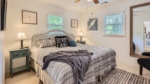 A bedroom with a bed, two nightstands, a ceiling fan, and a large mirror. - Locke Haven (Sherrills Ford)