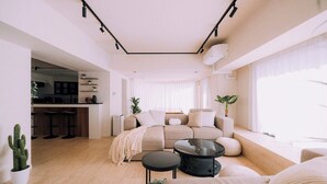 A modern living room with a sofa, coffee table, and a kitchen area in the background.