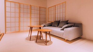 Une pièce comprenant un canapé, deux petites tables rondes et des panneaux coulissants de type shoji.