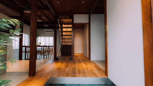 Un intérieur moderne avec un plancher en bois, un escalier et un coin repas comprenant des chaises et une table.
