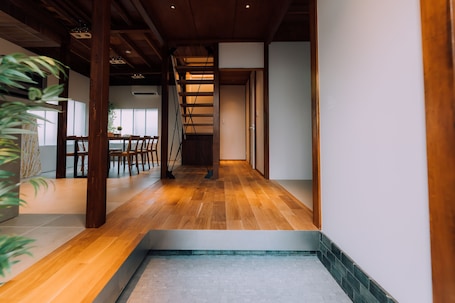 A modern interior with a wooden floor, a staircase, and a dining area with chairs and a table.