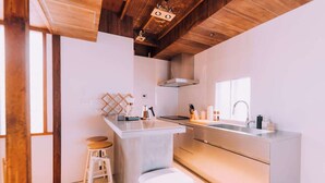 Une cuisine moderne avec un plafond en bois, un îlot central doté de tabourets, un évier et une cuisinière.