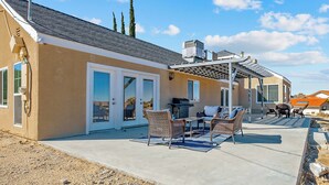 Une maison avec un patio, du mobilier d’extérieur et un barbecue.
