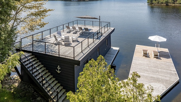 A modern dock with a deck, outdoor seating, and a staircase leading to a building. - 4bed, 4bath, South exp, prestigious area of Royal Muskoka Island w/road access (Minett)