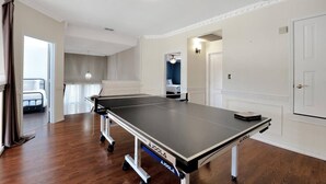 Une pièce avec une table de ping-pong, un lit et une salle de bain visible à travers une porte ouverte.