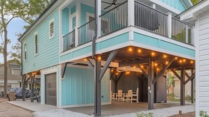 A two-story house with a balcony, outdoor seating area, and a garage. - Ocean Lakes New Build, Steps to Beach and Balcony! (Myrtle Beach)