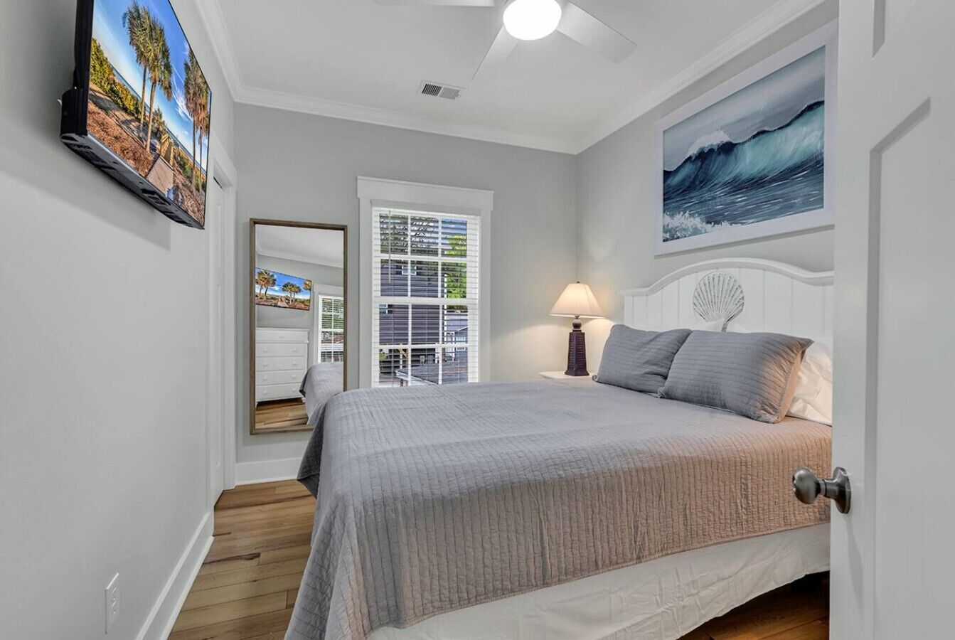 A bedroom with a bed, a nightstand, a lamp, a window, and a painting on the wall.