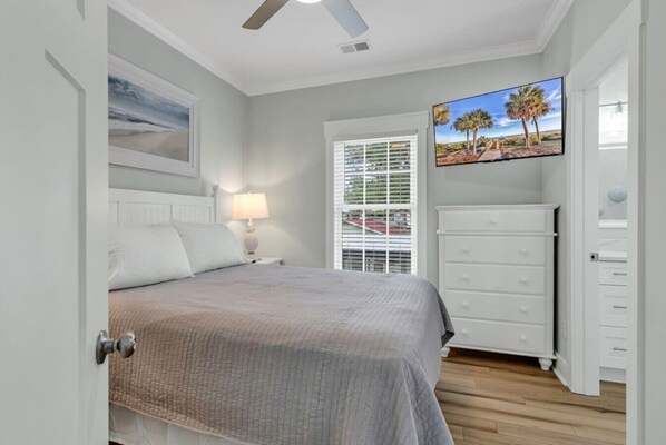 A bedroom with a bed, a nightstand, a dresser, a window with blinds, and a ceiling fan.