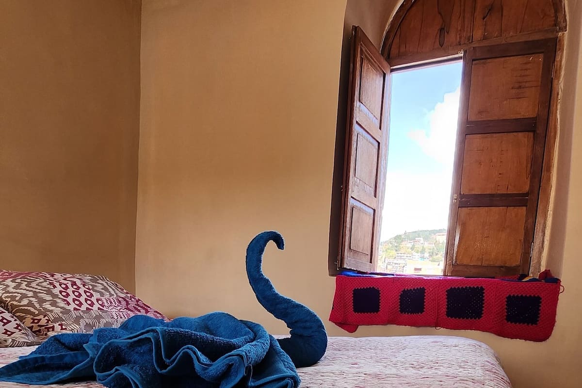 A bedroom with a floral bedspread, a blue blanket, and a wooden door leading to a balcony.