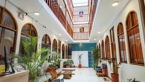 A spacious indoor area with a high ceiling, wooden railings, and multiple potted plants. - Munay Cusco (Cusco)