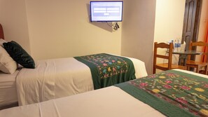 A hotel room with two beds, a television mounted on the wall, and a chair. - Munay Cusco (Cusco)