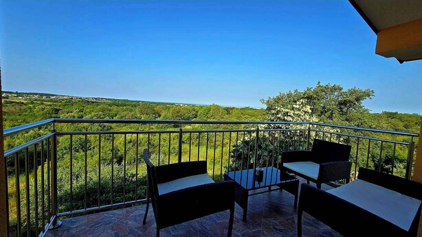 Ein Balkon mit Tisch und Stühlen mit Blick auf eine grüne Landschaft.