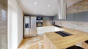 Eine moderne Küche mit Einbauofen, Edelstahlkühlschrank und einer Holzarbeitsplatte.