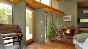 Une pièce chaleureuse avec une cheminée en pierre, un bureau en bois et un lit confortable.