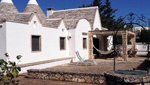 A white building with stone accents, a stone wall, and a hammock.