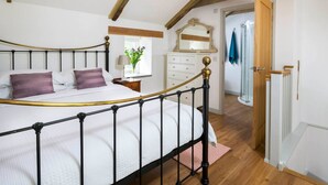 Un dormitorio con cama con dosel, cómoda, espejo y puerta que da al baño.