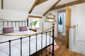 Une chambre à coucher avec un lit à baldaquin, une commode, un miroir et une porte donnant sur une salle de bain.