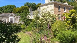 A large stone house with a well-maintained garden and a clear blue sky. - The Hayloft - A Romantic Boutique Retreat (Camborne)