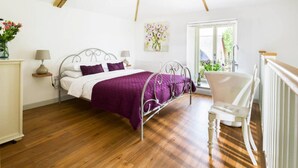 Un dormitorio con cama, una silla, un ventanal y un radiador.