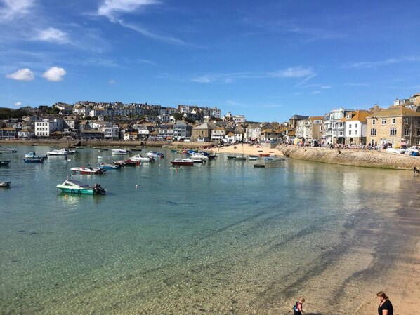 A coastal town with clear waters, boats, and buildings along the shore. - Bramble’s Cottage (Cornwall)