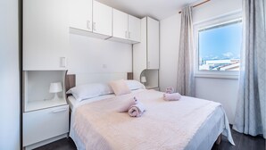Una camera d'albergo moderna con un letto grande, un comodino, un armadio e una finestra con vista sulla città.