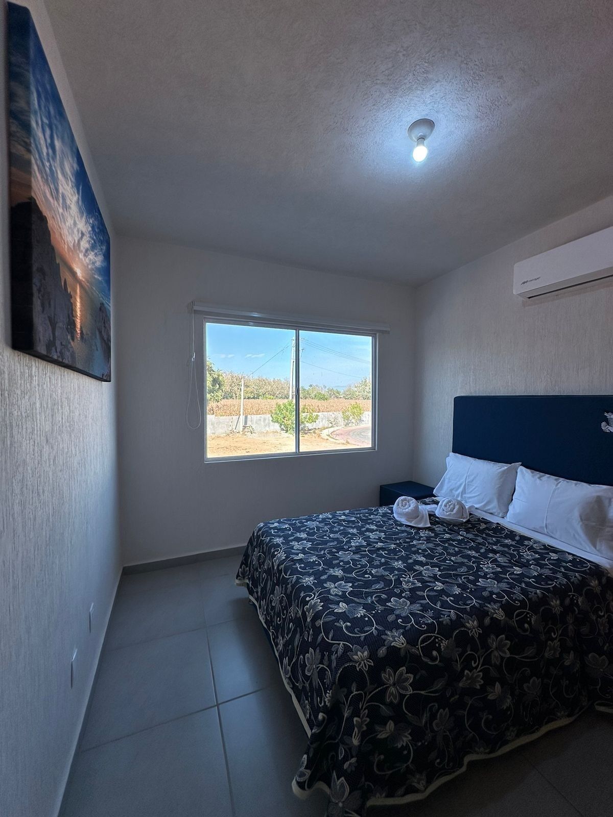A bedroom with a bed, a window, and a ceiling light.