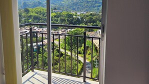 A balcony with a view of a mountainous landscape and a residential area.