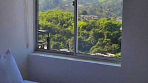 A bedroom with a large window offering a view of a mountainous landscape.