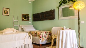 A room with a bed, a chair, a table with a lamp, and a mirror on the wall.