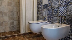 A bathroom with two white bidets, a sink, and a tiled wall with a blue and white pattern.