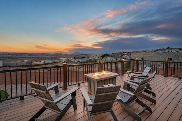 A deck with outdoor seating and a fire feature, overlooking a residential area.