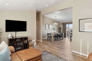 A living room with a TV, sofa, and a dining area with chairs and a table. - The Hideaway - 50 Mile Views, Sleeps 8, Big Garage (Page)