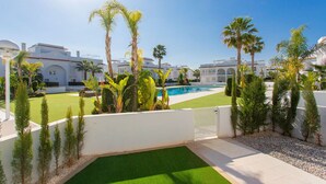 A pool area with palm trees, a white wall, and a clear blue sky. - CH Allegra 135 Doña Pepa (Ciudad Quesada) (Ciudad Quesada)