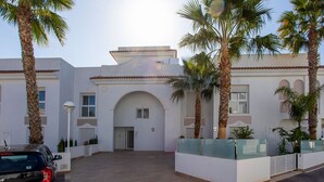 A building with a white facade, an arched entrance, and palm trees. - CH Allegra 135 Doña Pepa (Ciudad Quesada) (Ciudad Quesada)