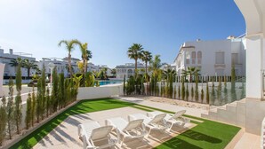 A poolside area with lounge chairs, palm trees, and a clear blue sky. - CH Allegra 135 Doña Pepa (Ciudad Quesada) (Ciudad Quesada)