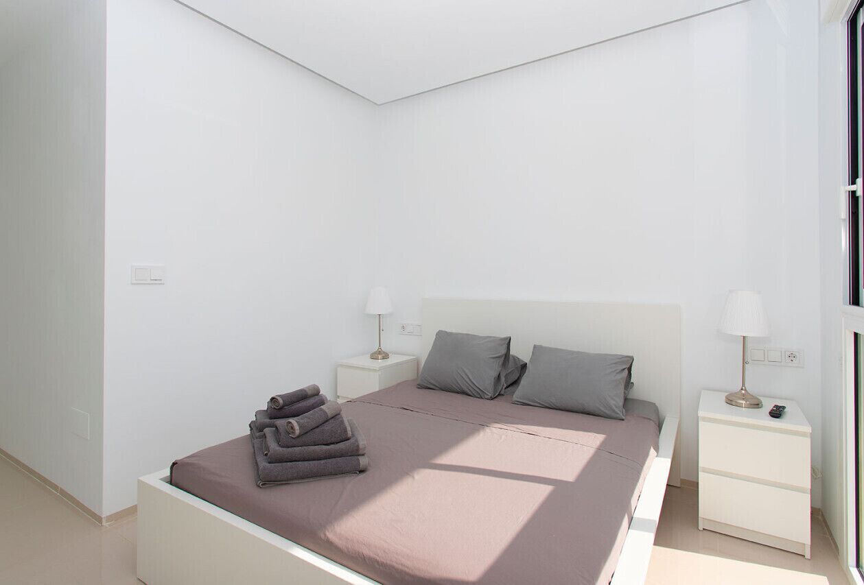 A modern bedroom with a bed, two bedside tables, and a window.