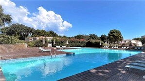 A swimming pool with lounge chairs and a wooden deck. - Location Corsica, T2 800 m from Cala Rossa Beach (Lecci)