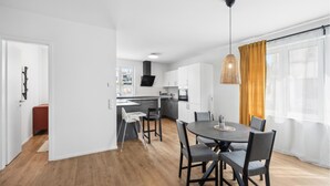 A modern kitchen with white cabinets, a black range hood, and a window with yellow curtains. - Awesome apartment in Lörrach with WiFi (Lörrach)