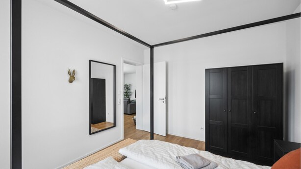 A modern bedroom with a large wardrobe, a mirror, and a bed with a pillow and blanket. - Awesome apartment in Lörrach with WiFi (Lörrach)