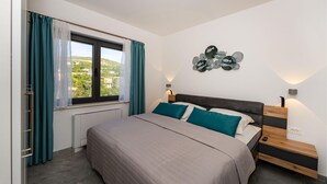 Ein Schlafzimmer mit einem Bett, einem Fenster mit Vorhängen, einer Wandleuchte und einem Wandbild.