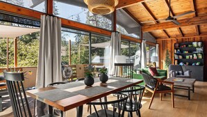 A modern interior with a wooden ceiling, large windows, a dining area with a table and chairs, and a cozy seating area with a sofa and armchairs. - Family Cabin, Dog, Ht Tb, 15 min Yosemite, Valentine's Day + Firefall Packages (Oakhurst)