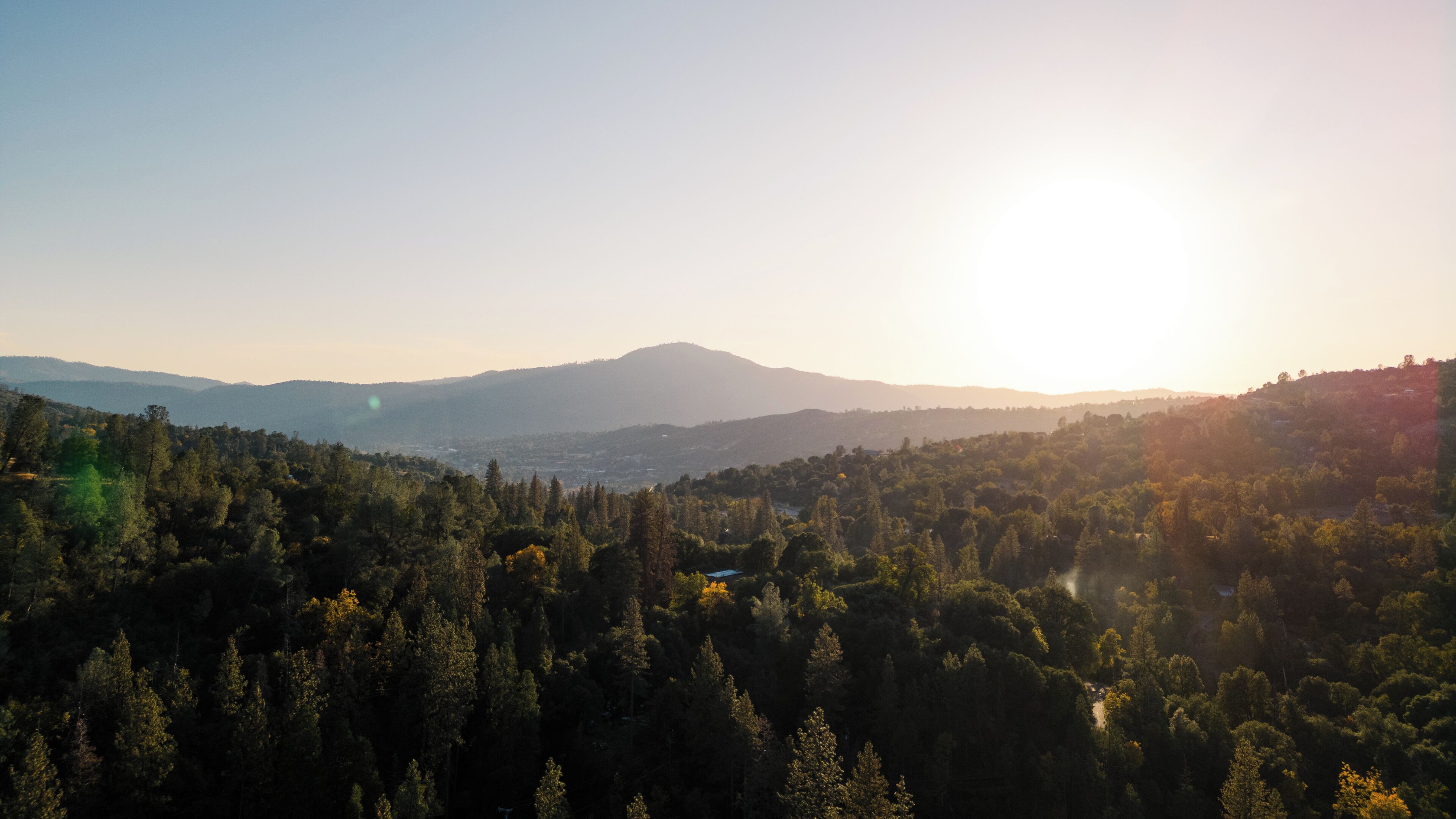 A mountainous landscape with dense forests and a clear sky.