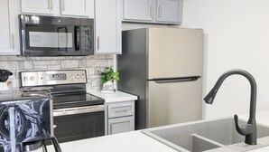 Una cucina moderna con mobili bianchi, elettrodomestici in acciaio inossidabile, un rubinetto nero e un soffitto in legno.