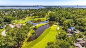 A golf course with a water hazard, surrounded by residential areas and a body of water in the background. - Ocean Pines 3BR House Resort Community (Berlin)
