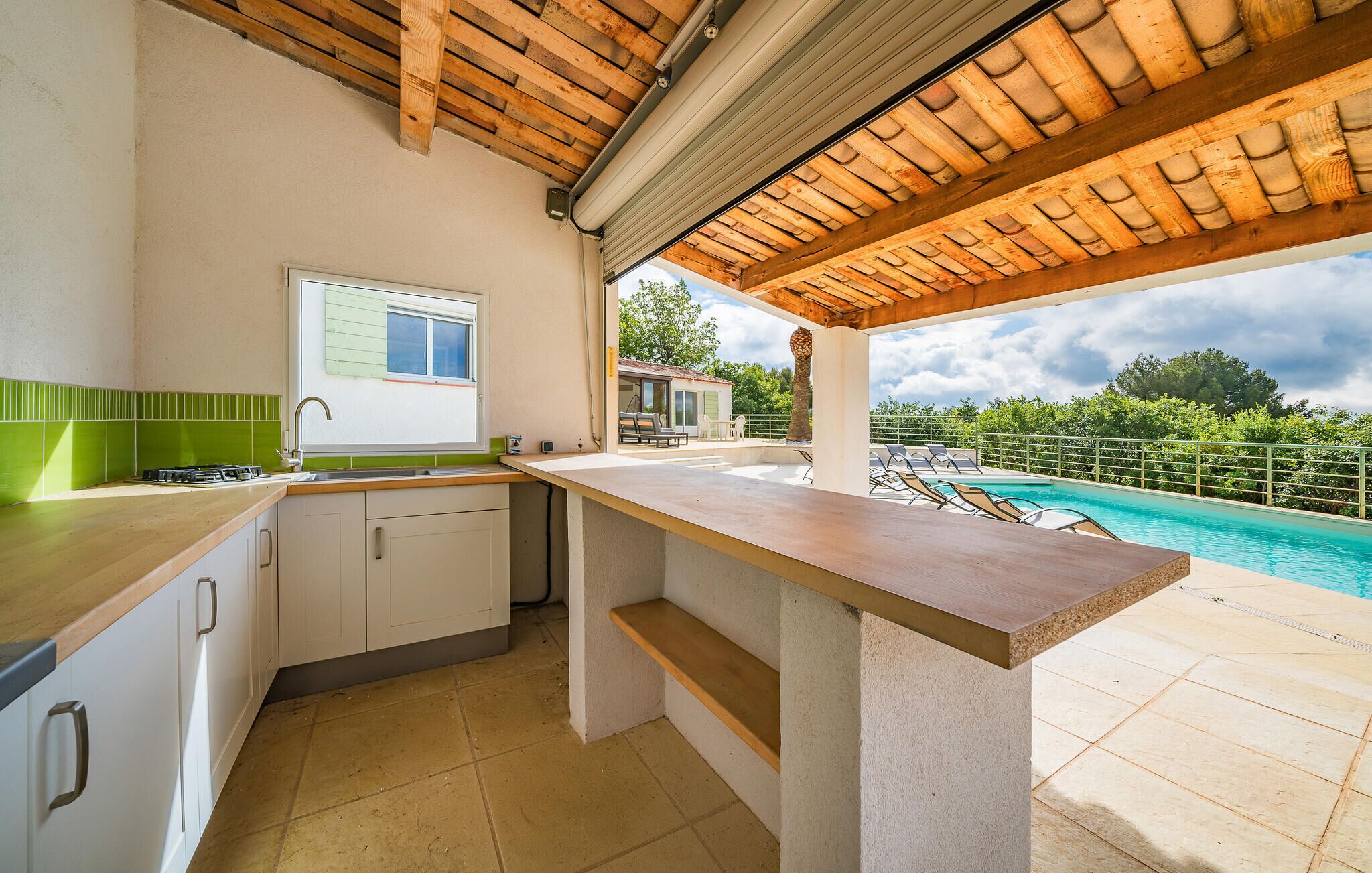 A kitchen with a view of a pool and a small outdoor seating area.