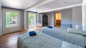 Une pièce spacieuse avec un grand lit, une armoire et une salle de bain visible à travers une porte ouverte.