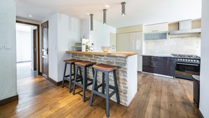 Une cuisine moderne dotée d’un îlot central en pierre, de tabourets de bar, d’une cuisinière et d’un grand four.