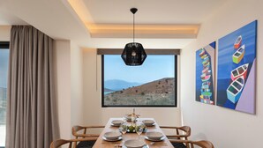 Un coin repas avec une table dressée pour six personnes, une vue sur l’extérieur et des œuvres d’art accrochées au mur.