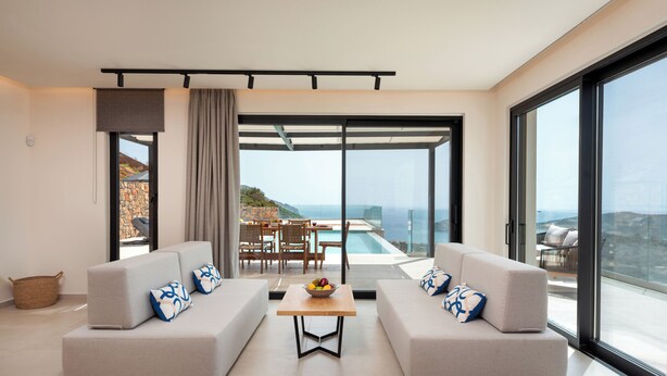Un salon moderne avec deux canapés, une table basse et un coin repas offrant une vue sur la piscine.